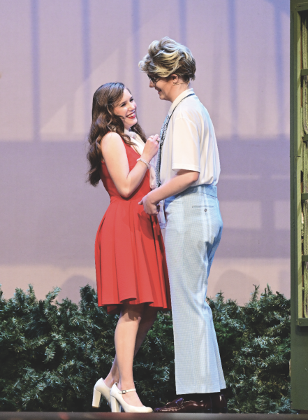 Sophomore Ellie Roberts and senior Lily Rieff flirt May 23 in the Auditorium. Roberts played a con woman named Ashley Johnson in the Spring play ‘The Wedding Grift’. “Our character were supposed to be getting to know eachother in the background of our parents talking about us,” Roberts said. 
photo by Ashley Broils